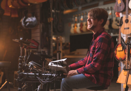 Smiling young man playing the drums in a music store