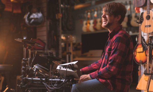 Smiling young man playing the drums in a music store