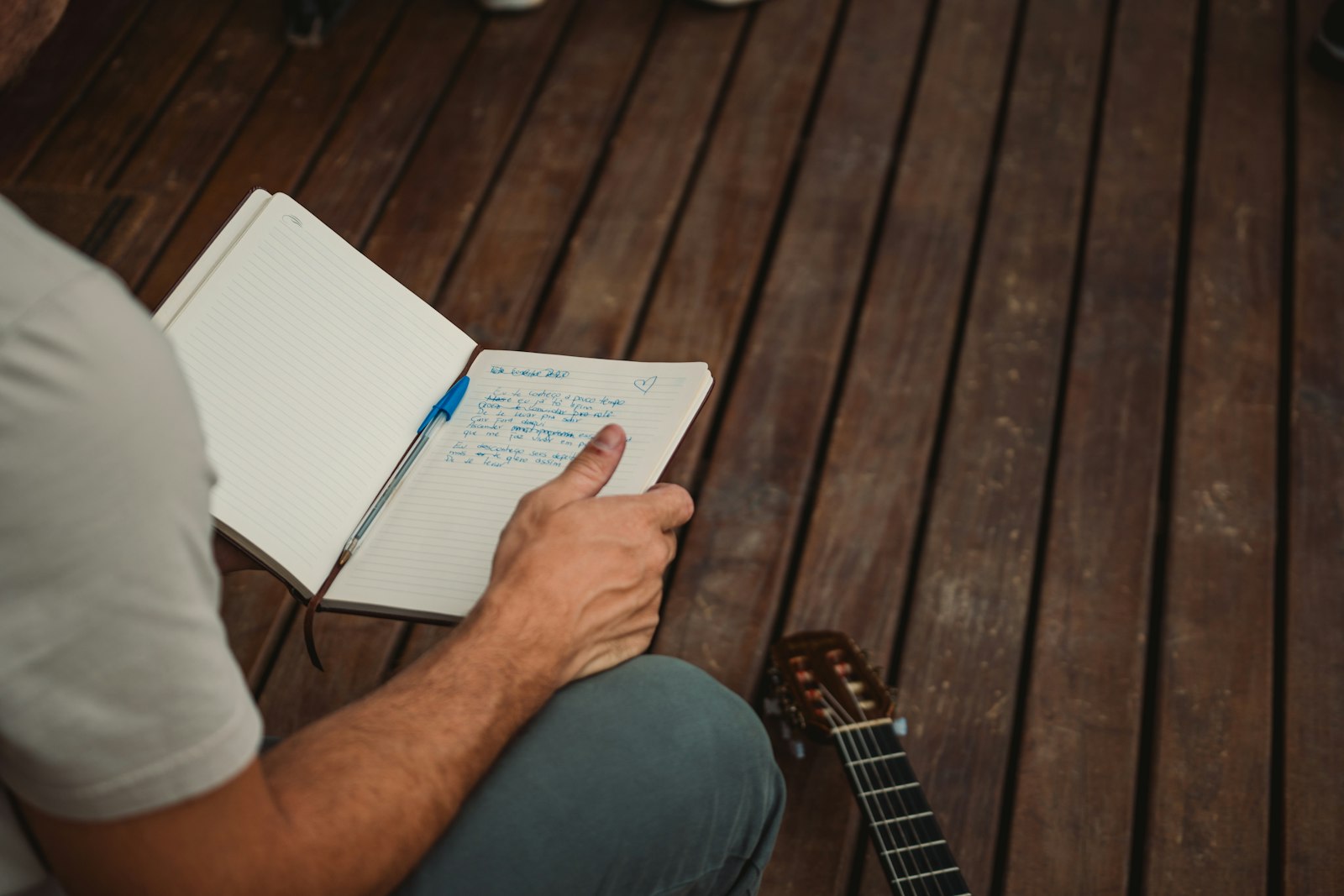 Musicien assis sur un parquet, carnet en main, notant les idées d’arrangement