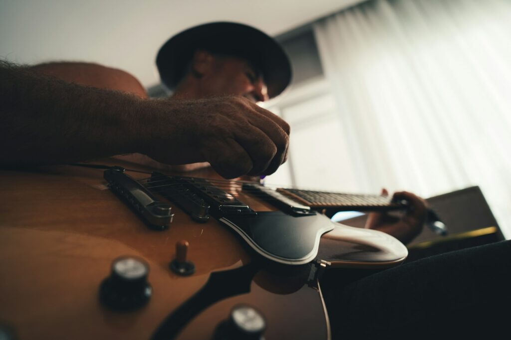 Musicien jouant de la guitare devant une fenêtre, en train de travailler un arrangement