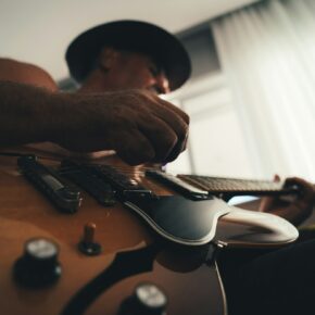 Musicien jouant de la guitare devant une fenêtre, en train de travailler un arrangement