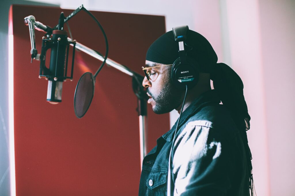 Chanteur enregistrant une voix principale devant un micro à condensateur en studio