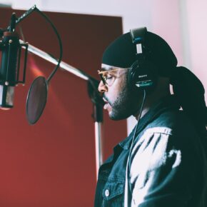 Chanteur enregistrant une voix principale devant un micro à condensateur en studio