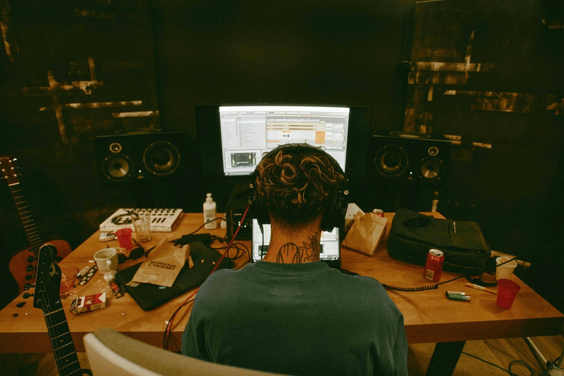 Musicien assis à son bureau avec une guitare, en train de travailler sur les titres de sa prochaine sortie