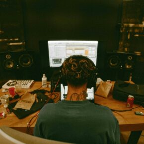 Musicien assis à son bureau avec une guitare, en train de travailler sur les titres de sa prochaine sortie
