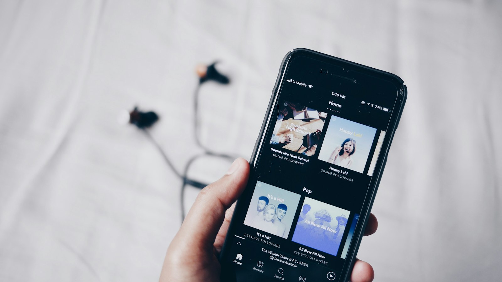 Main tenant un smartphone affichant une application d’écoute musicale en streaming