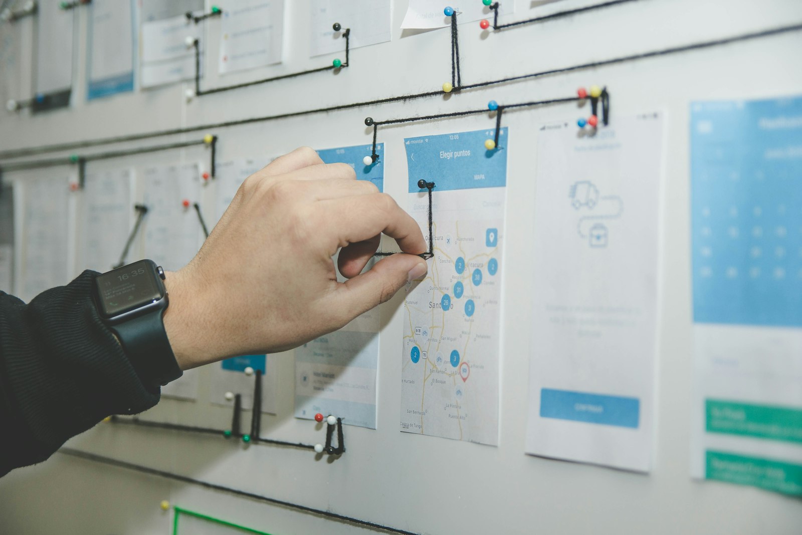 Personne organisant des feuilles et des notes sur un tableau mural