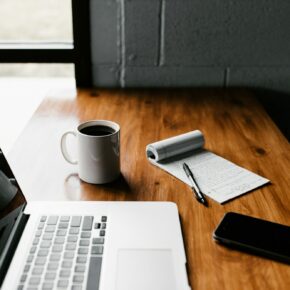 Ordinateur portable, tasse blanche et smartphone sur une table lumineuse