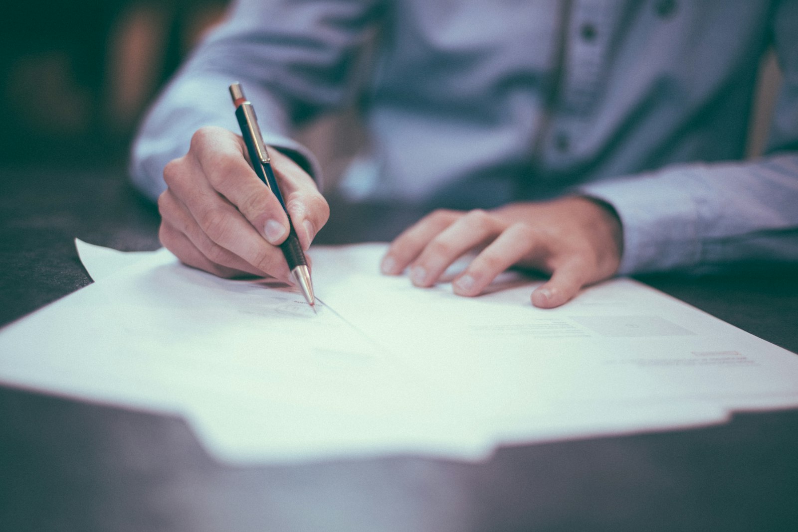 Personne signant un document papier sur une table