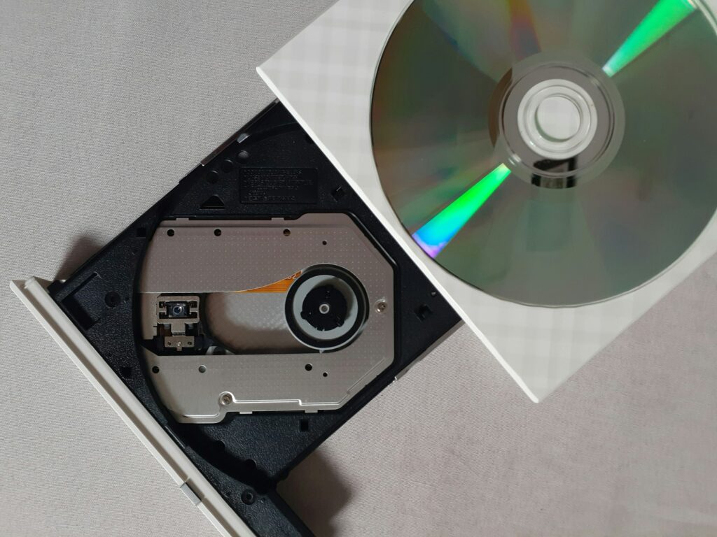 Disque compact argenté posé sur un lecteur CD noir, vue de dessus