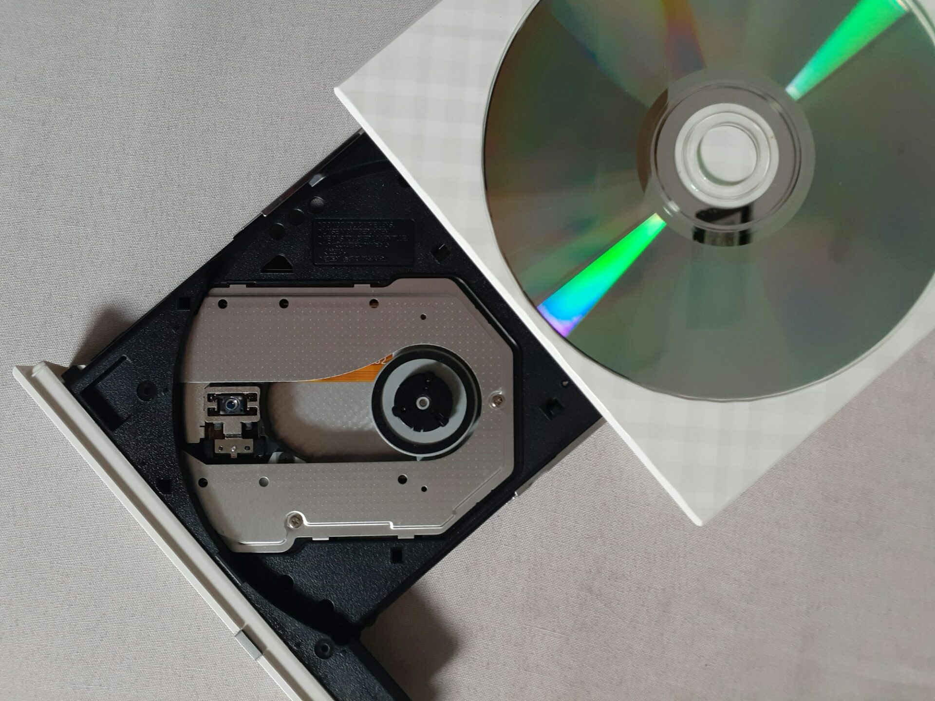 Disque compact argenté posé sur un lecteur CD noir, vue de dessus