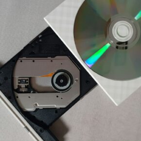 Disque compact argenté posé sur un lecteur CD noir, vue de dessus