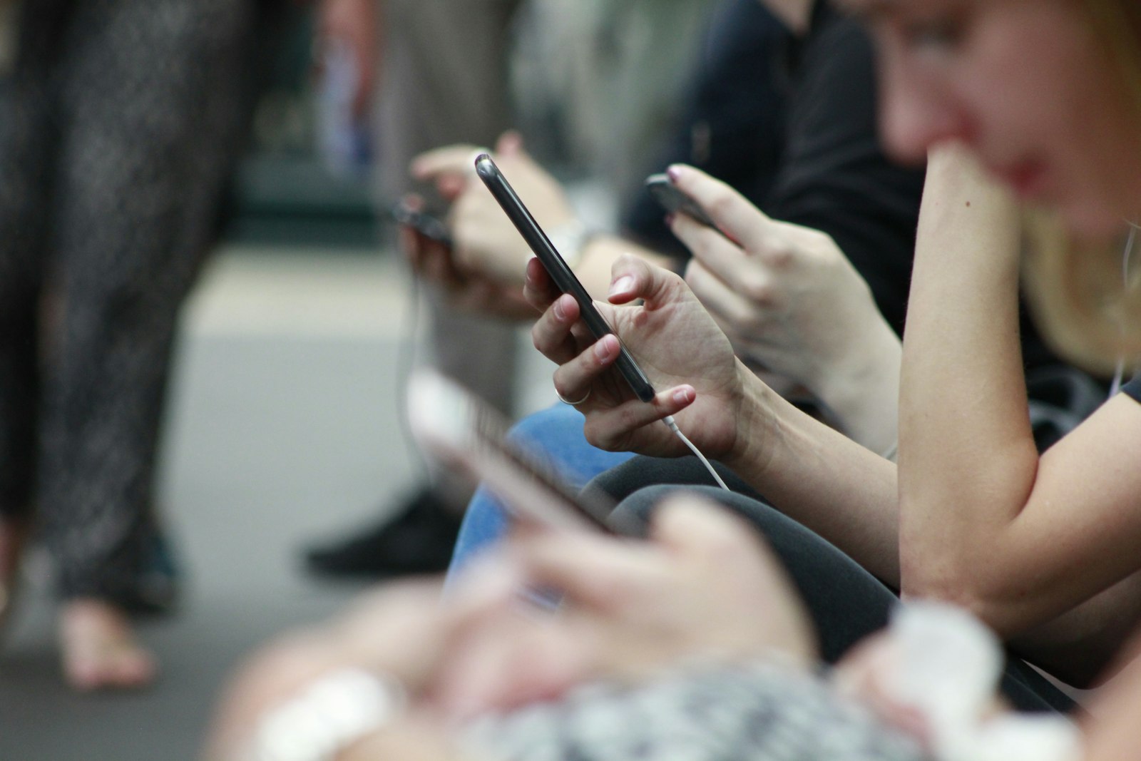 Rangée de mains tenant des smartphones et faisant défiler des contenus