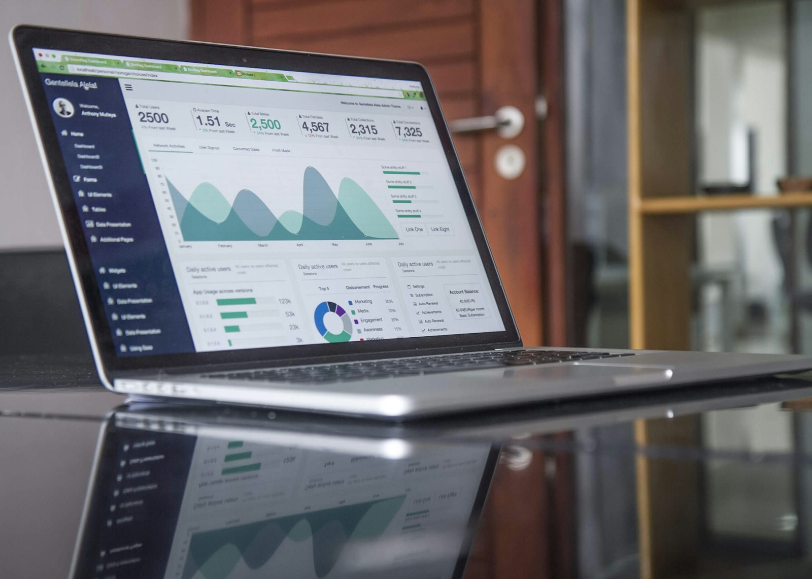 Ordinateur portable affichant des graphiques statistiques sur une table en verre
