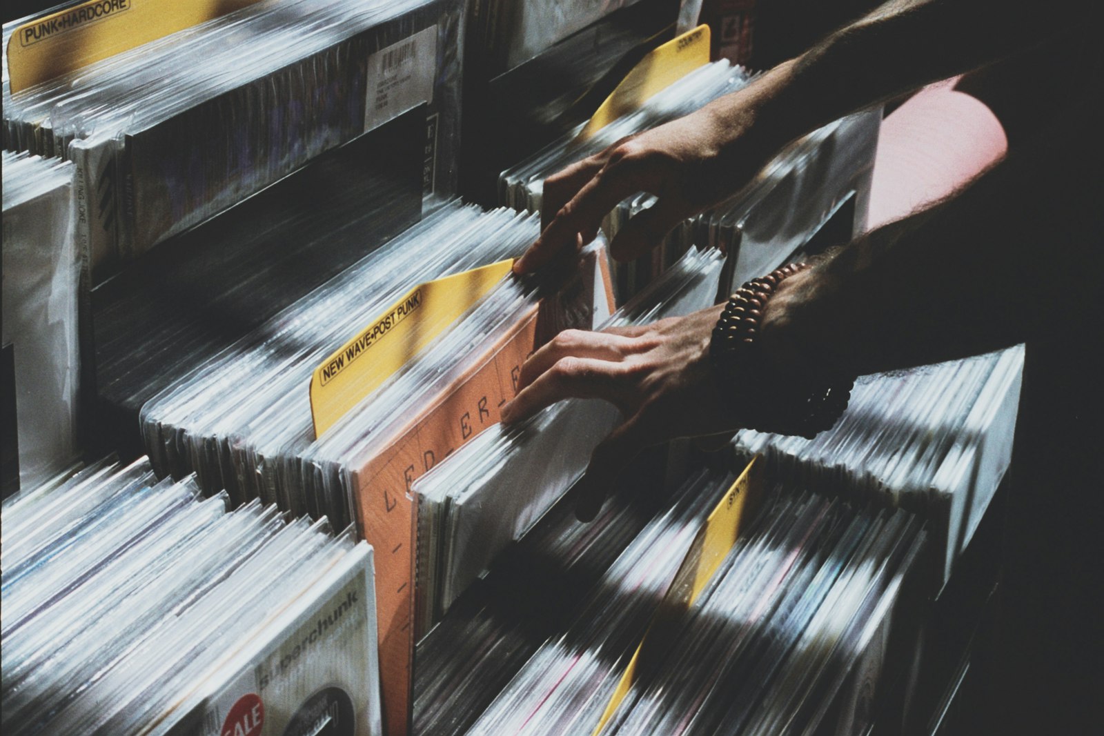 Personne photographiant des pochettes de vinyles dans un bac de disquaire
