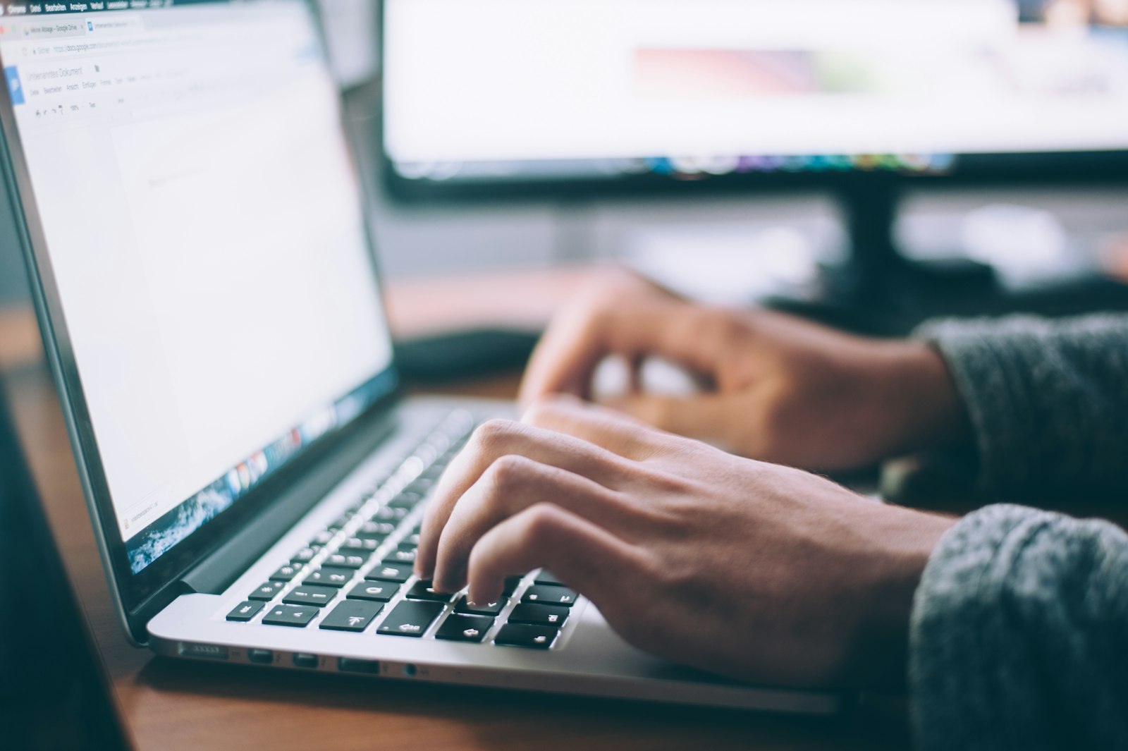 Mains sur le clavier d’un ordinateur portable en train de rédiger un message