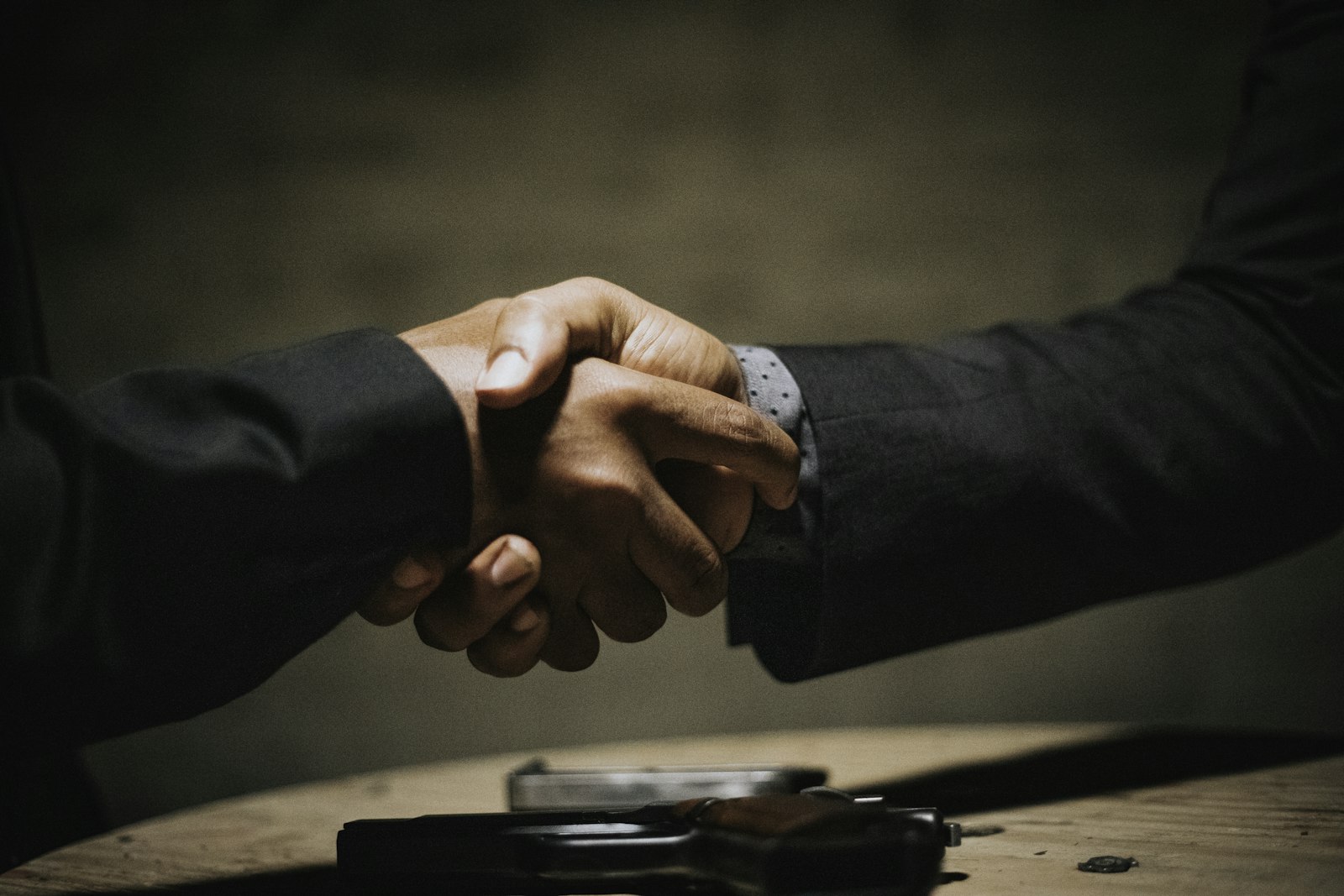 Deux personnes se serrant la main au-dessus d’une table en bois