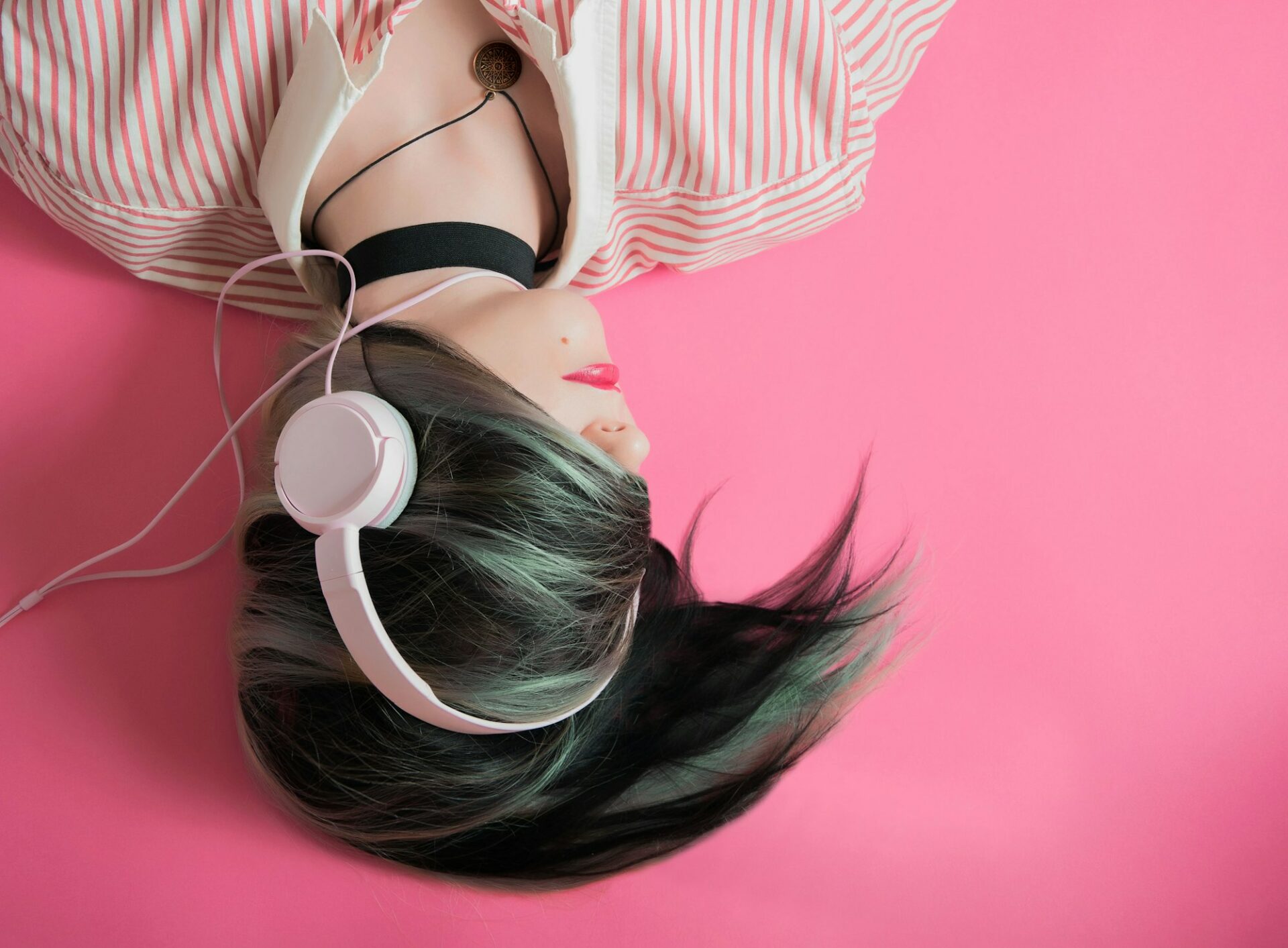 Personne écoutant de la musique au casque sur fond rose