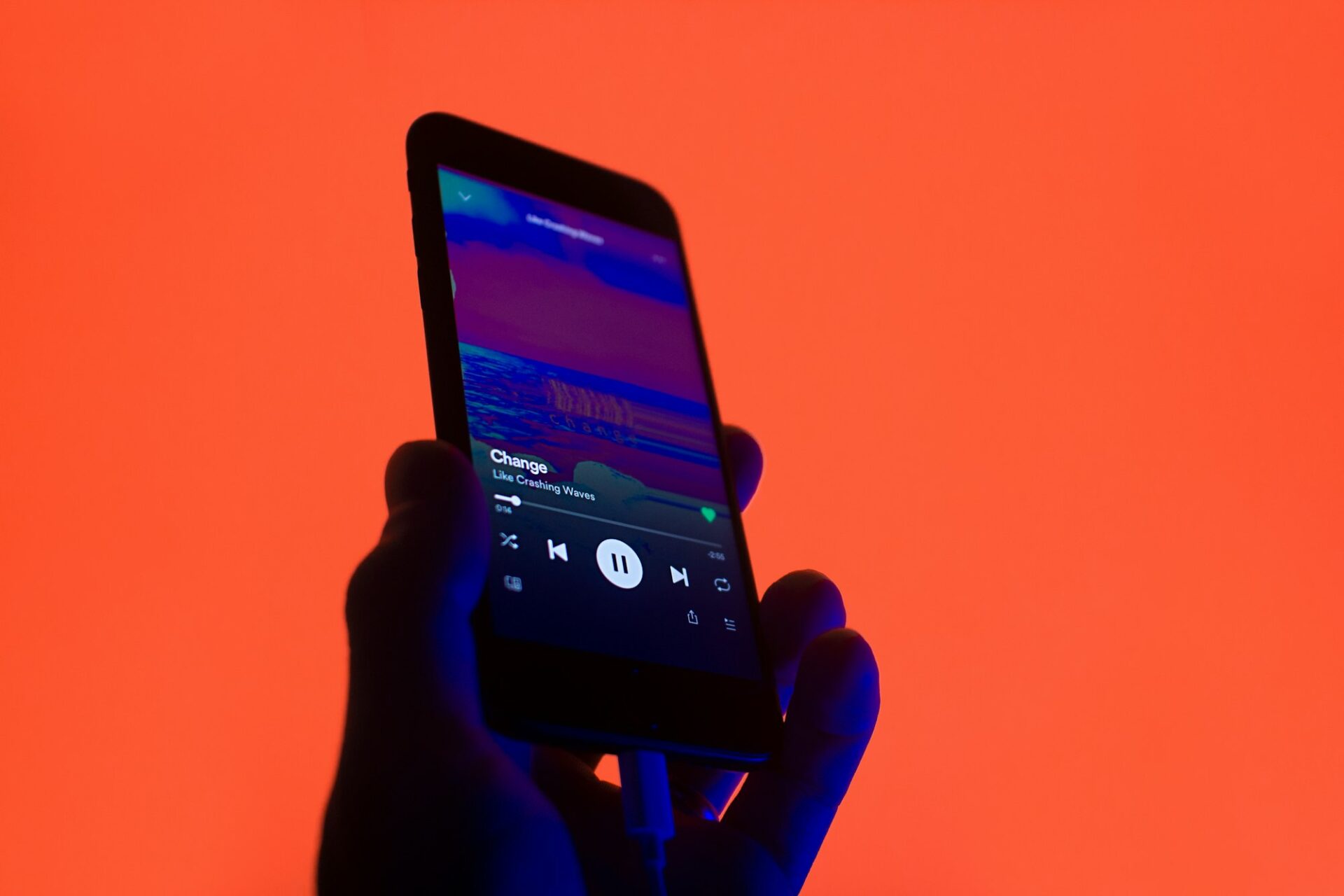 Main tenant un smartphone affichant une application d’écoute musicale