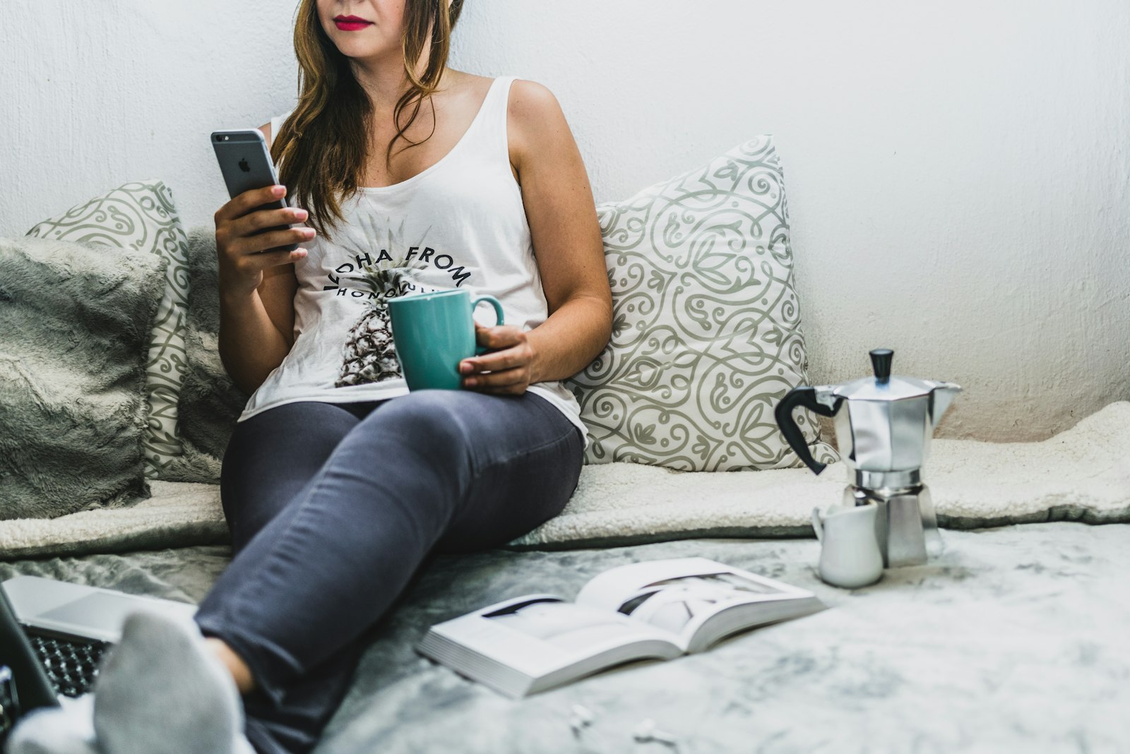 Personne consultant son smartphone devant une tasse de café
