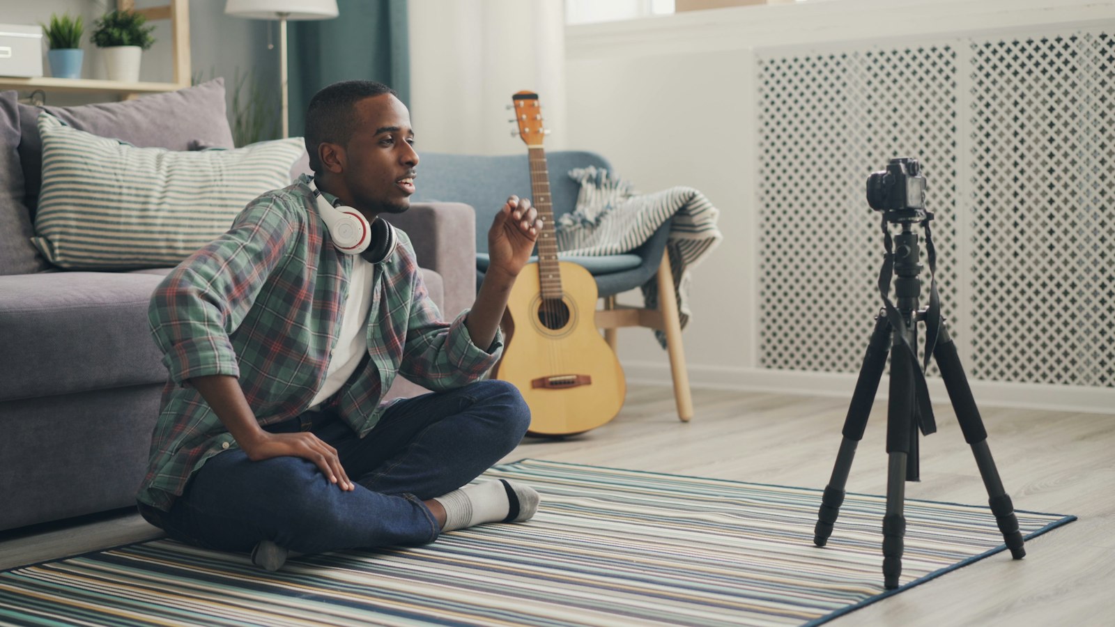 Musicien assis au sol jouant de la guitare dans un intérieur lumineux
