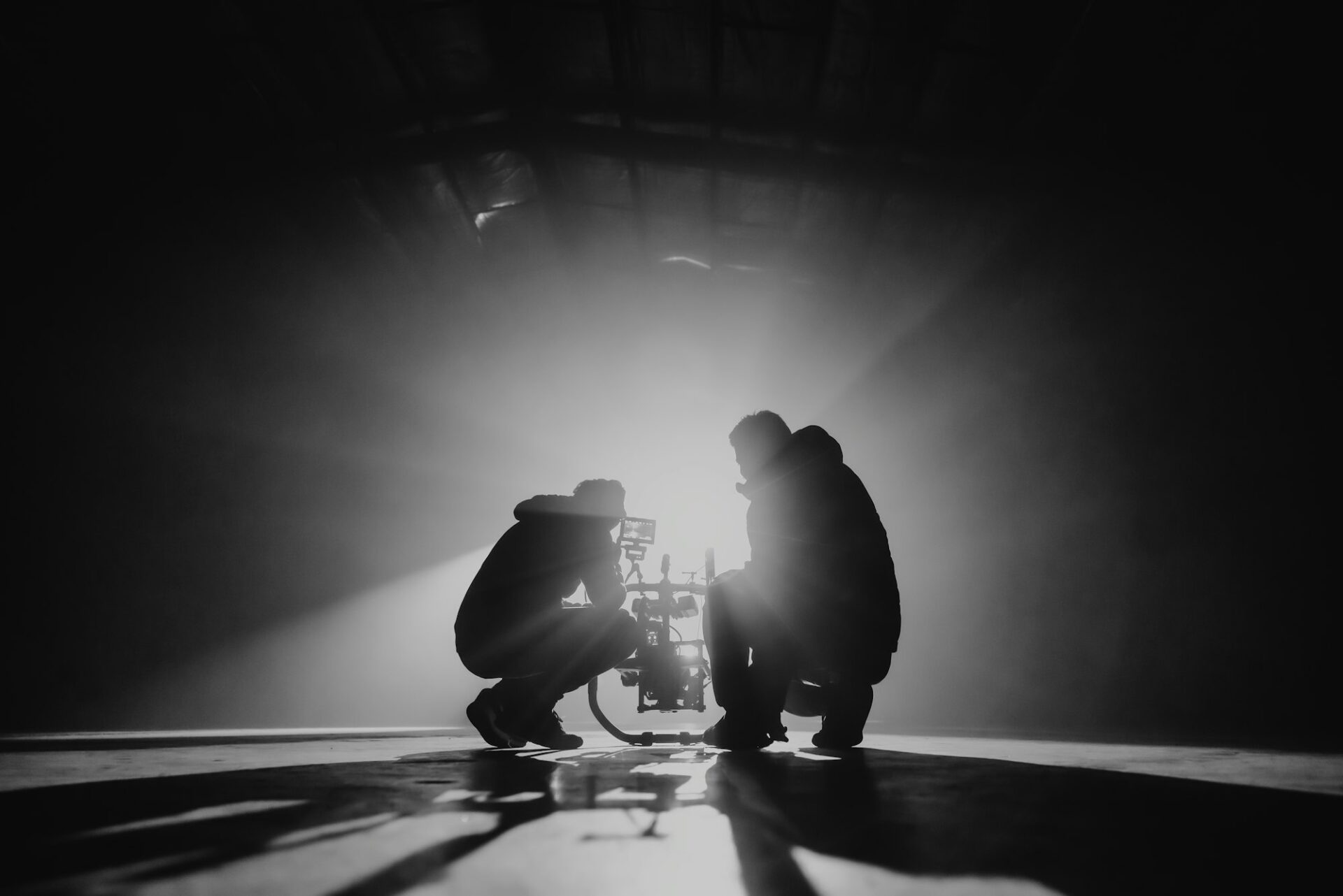 Réalisateur et producteur accroupis préparant un plan avant le tournage, en noir et blanc