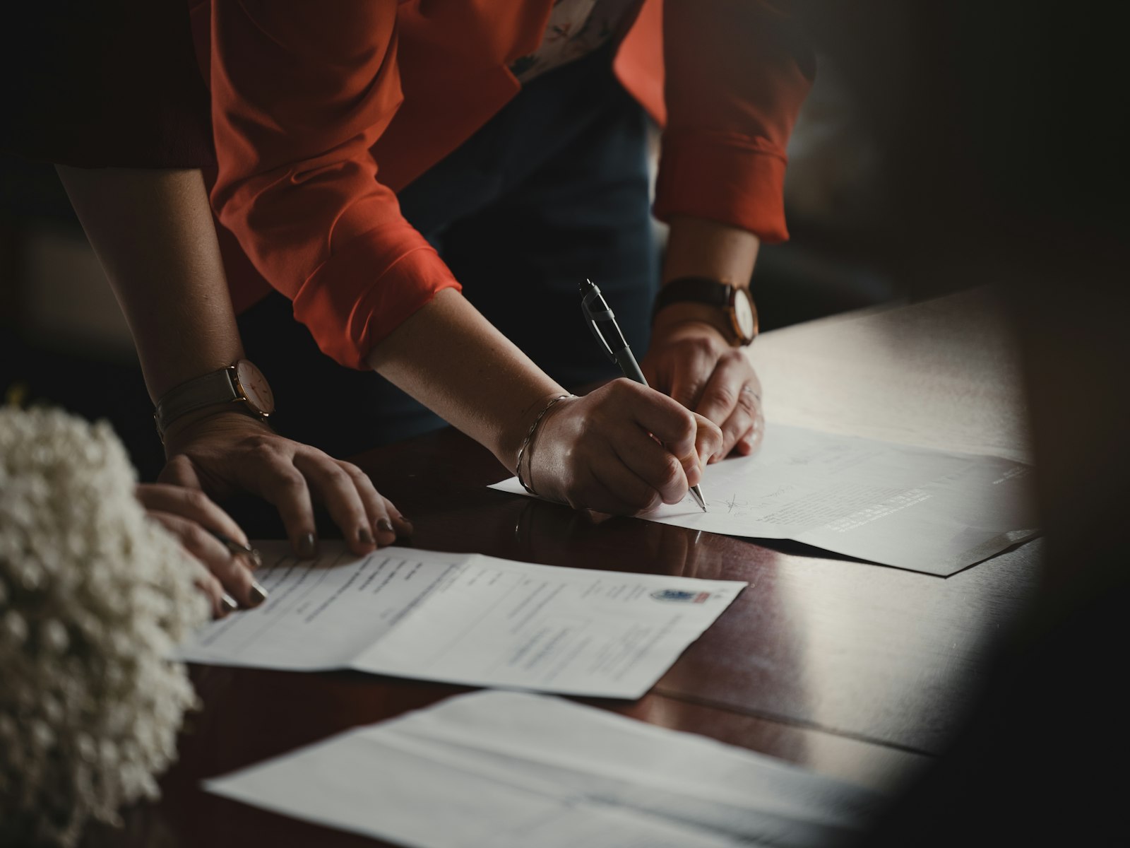 Main signant un document posé sur une table
