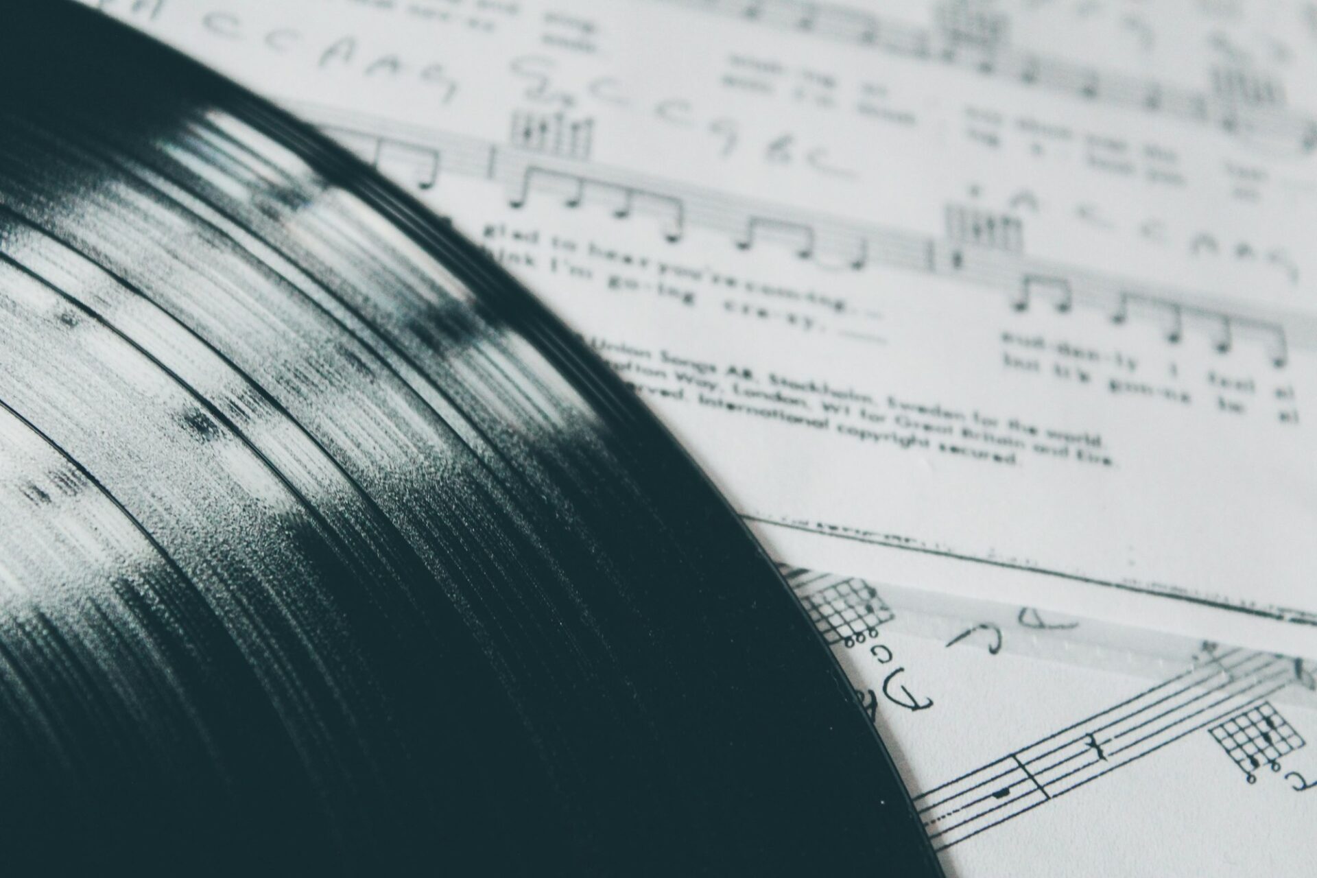 Feuille de paroles posée à côté d’un disque vinyle, l’œuvre et l’enregistrement côte à côte