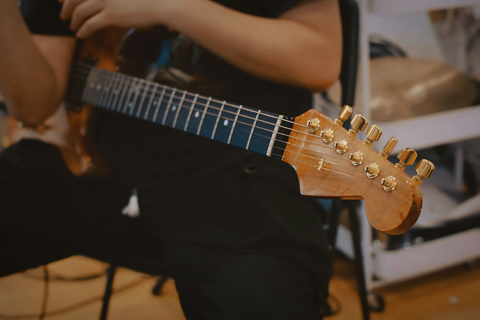 Personne jouant de la guitare dans une pièce faiblement éclairée