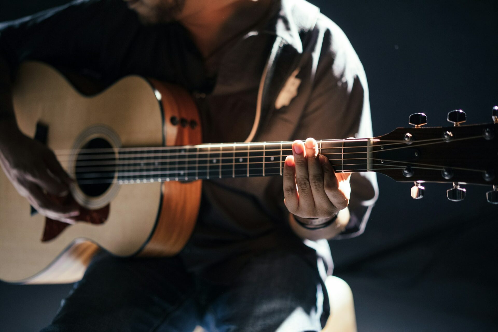 Guitariste jouant d’une guitare acoustique dans une lumière pâle