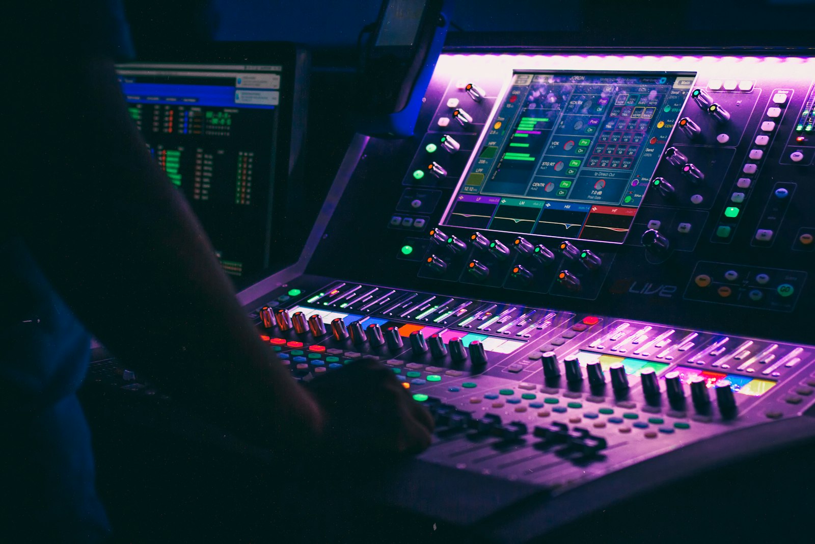 Mains d’un producteur manipulant un contrôleur audio en studio