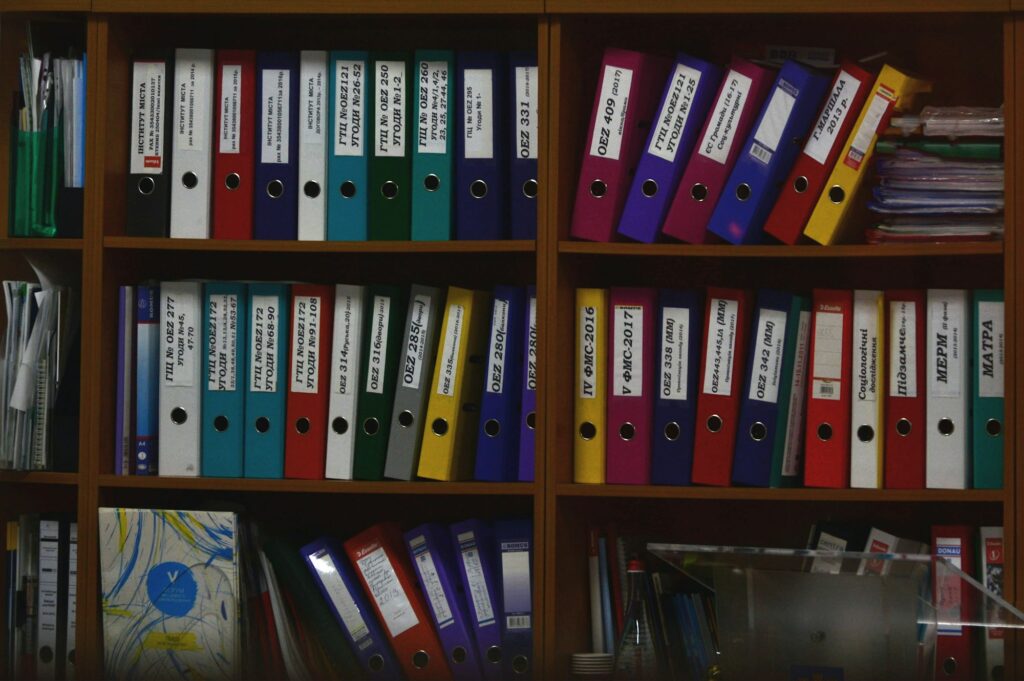 Rangées de classeurs colorés organisés sur des étagères en bois