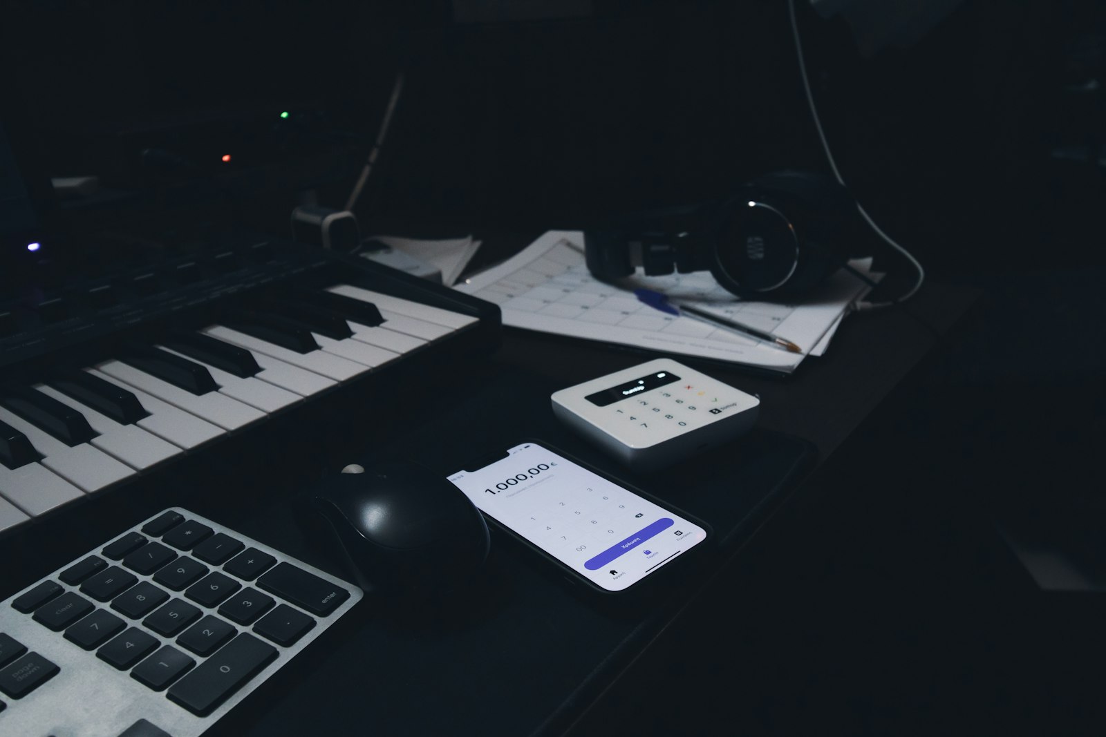 Clavier, souris et téléphone posés sur un bureau sombre