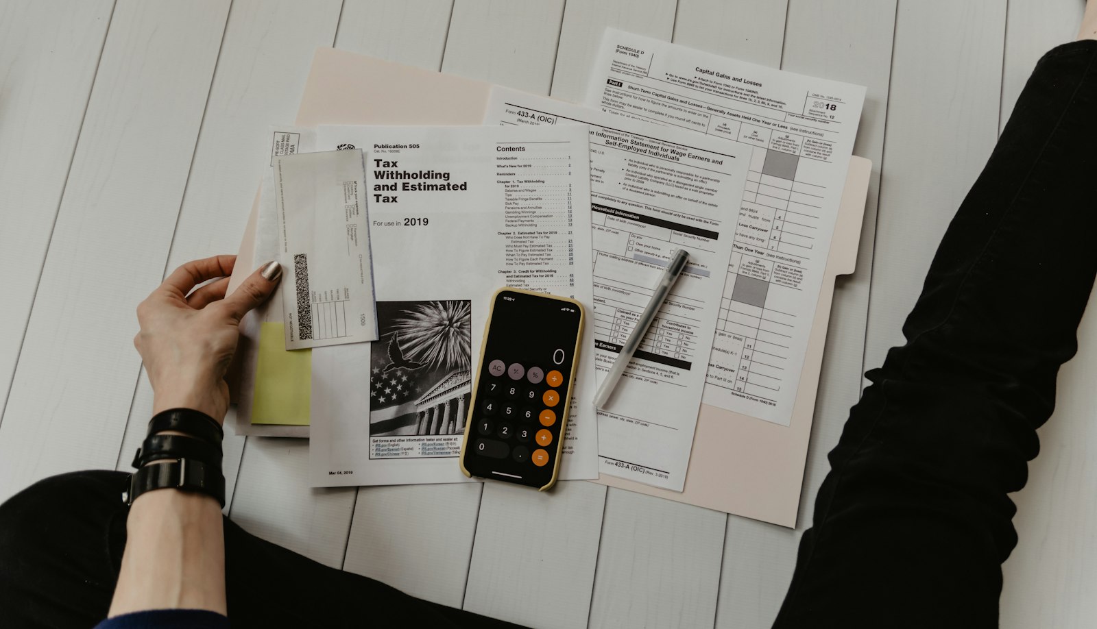 Personne tenant un relevé près d’un stylo et d’une calculatrice