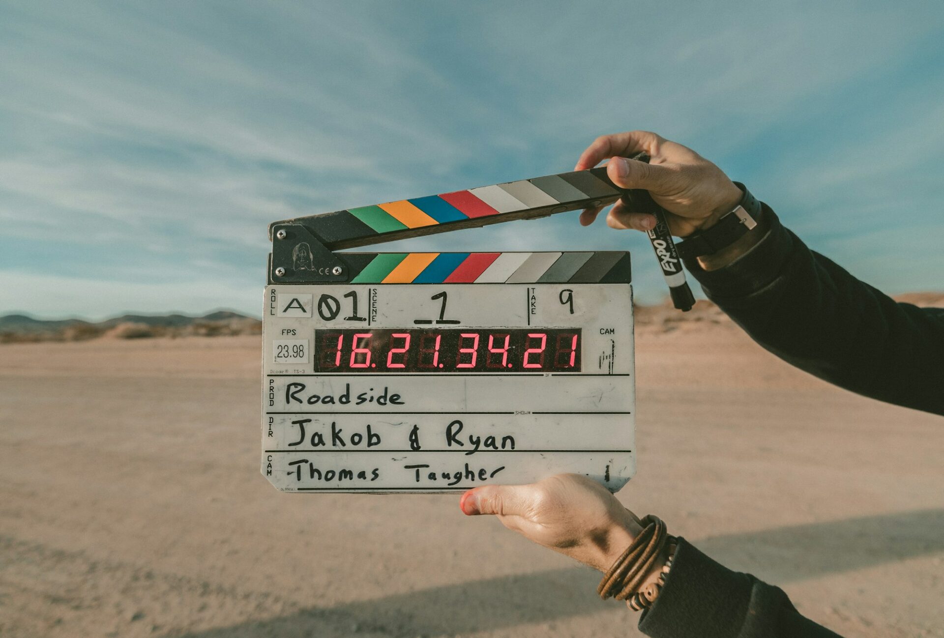 Clap de cinéma tenu devant une scène de tournage en extérieur