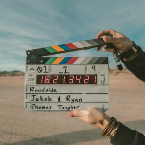 Clap de cinéma tenu devant une scène de tournage en extérieur