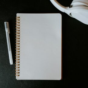 Carnet, stylo et casque audio posés sur une table