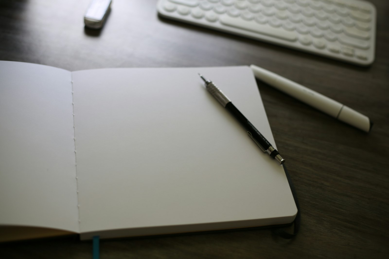 Carnet ouvert posé sur un bureau à côté d'un clavier