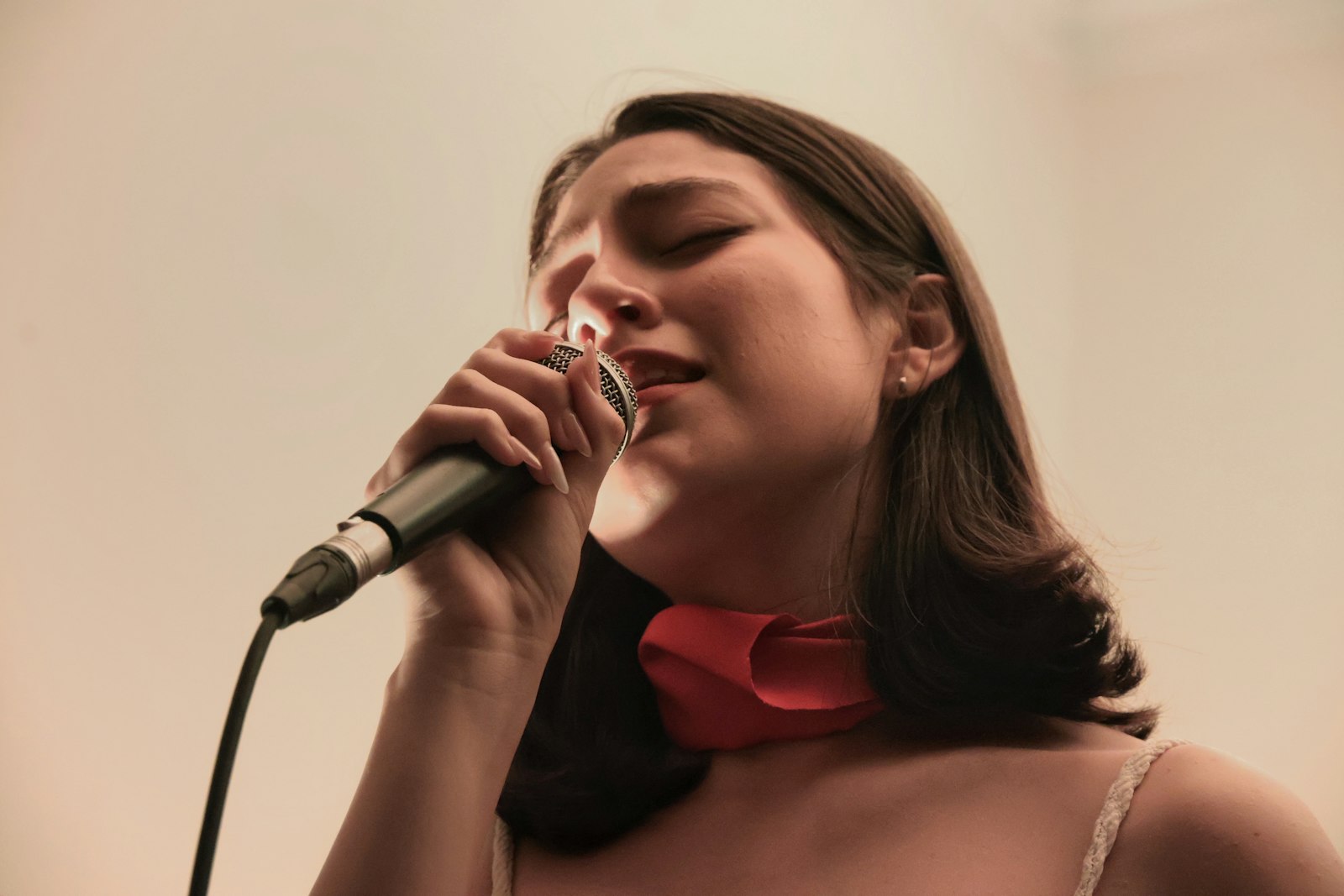 Femme chantant dans un microphone, les yeux fermés