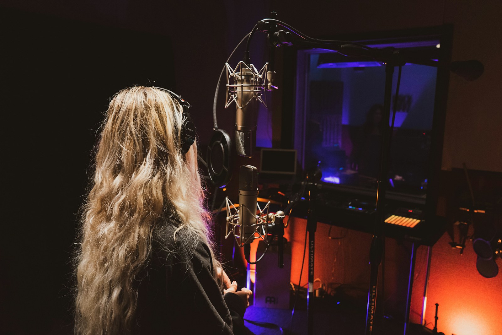 Chanteuse aux cheveux longs debout face à un micro pour une prise de voix