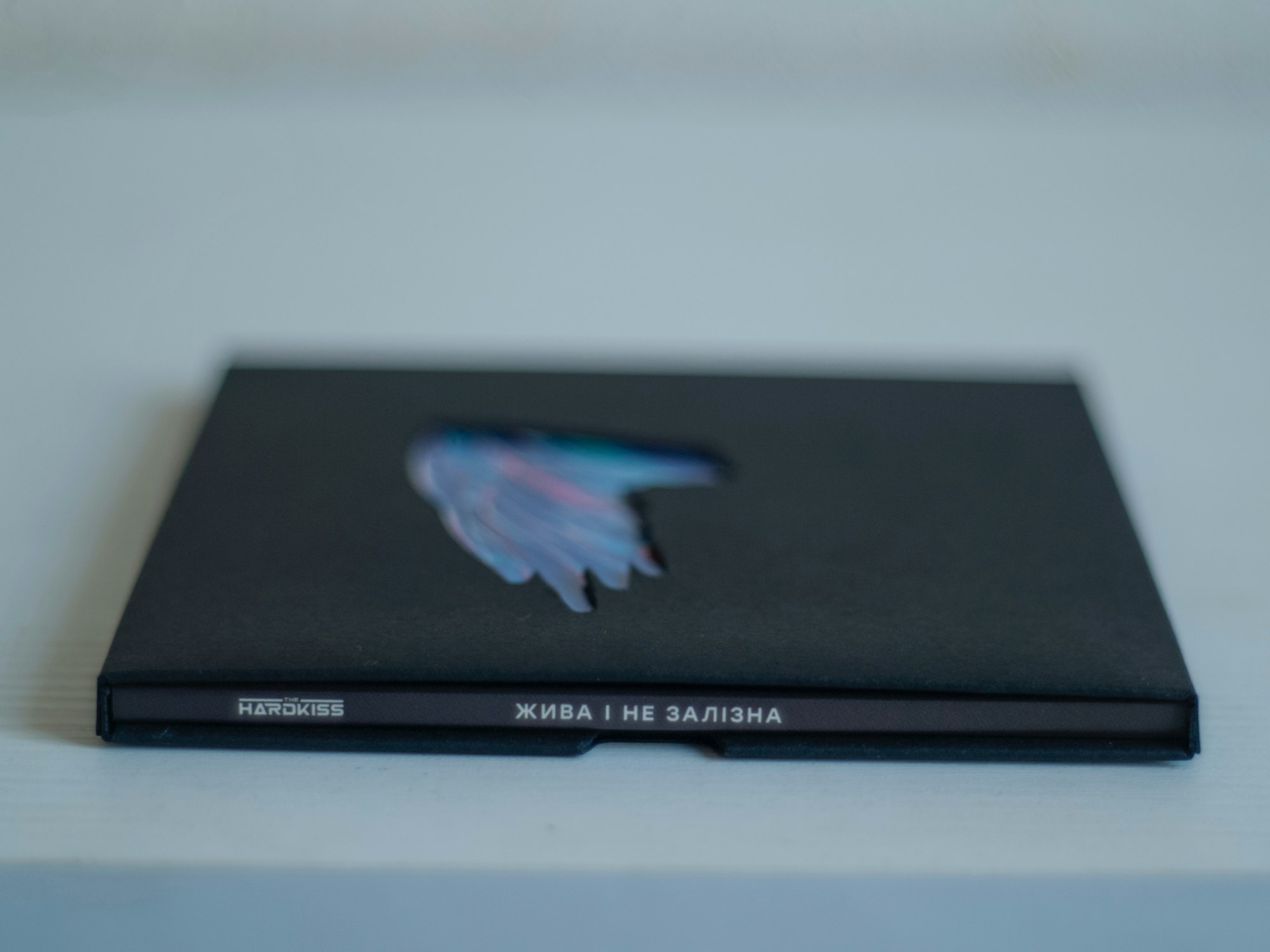 Boîtier de CD noir avec une découpe laissant apparaître une illustration abstraite colorée