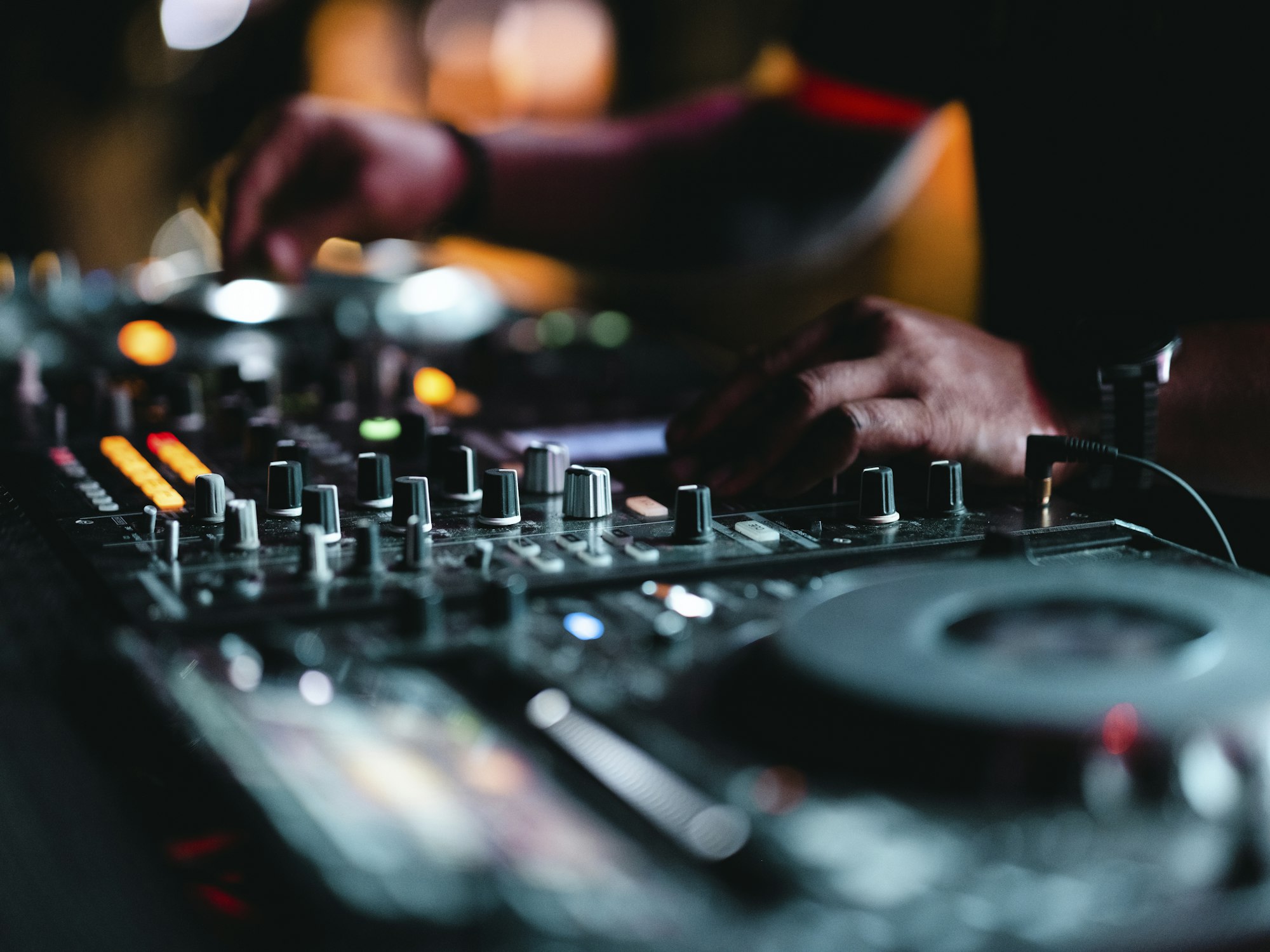 DJ aux platines dans une boîte de nuit, sous des lumières colorées