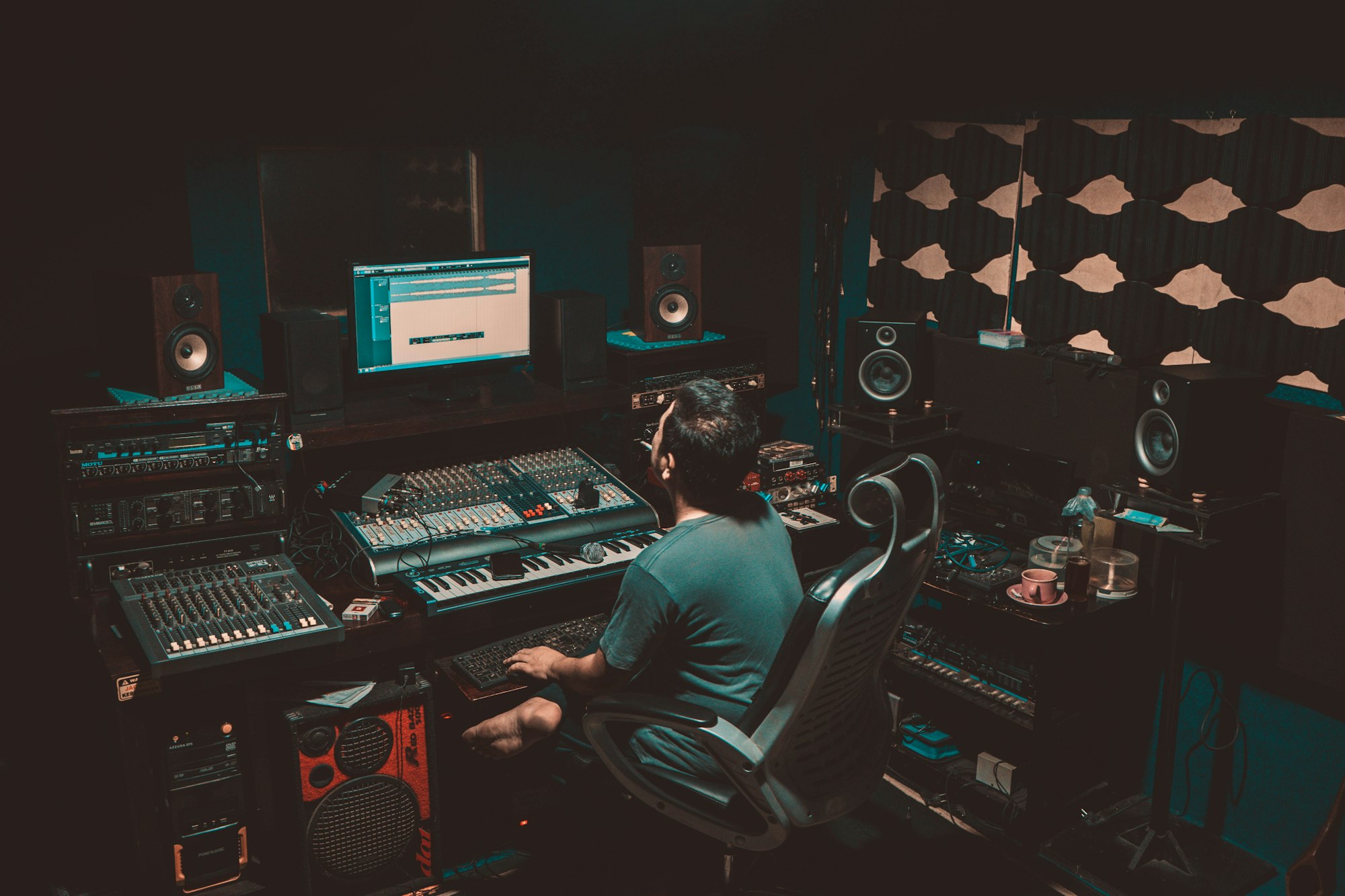 Musicien assis devant un écran d’ordinateur affichant un logiciel audio dans un home studio