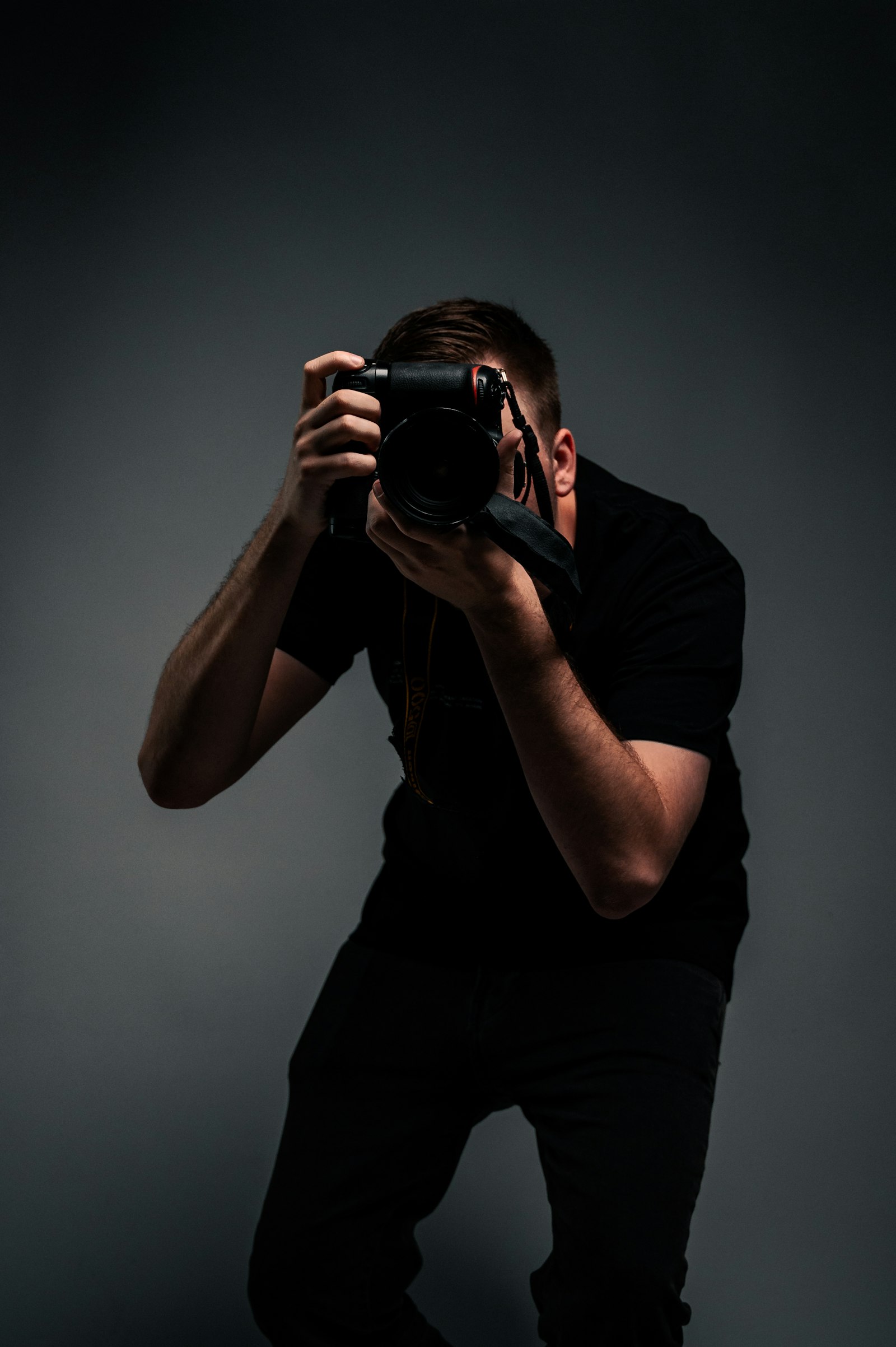 Homme en t-shirt noir tenant un appareil photo reflex