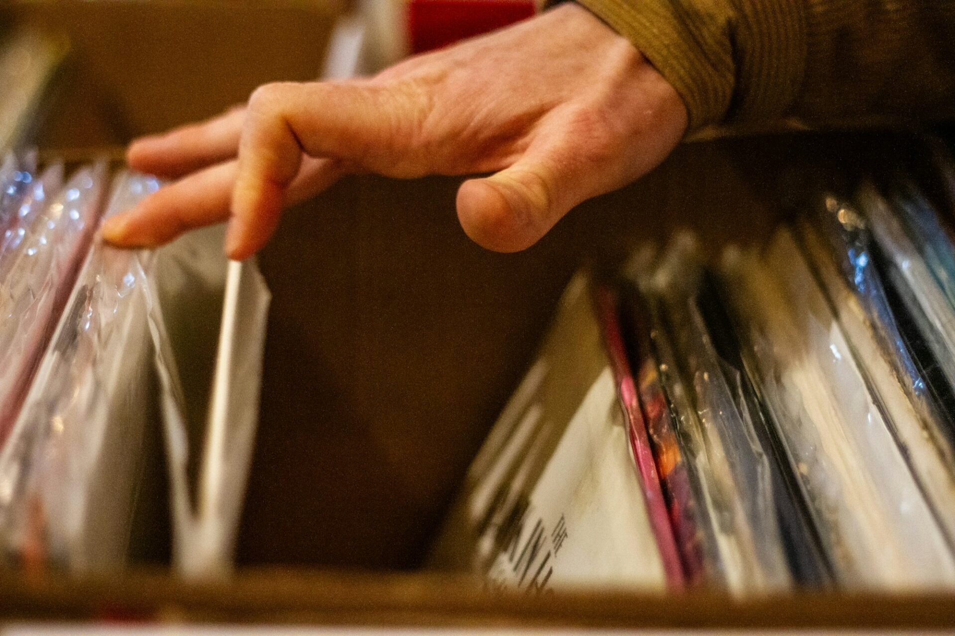 Main parcourant un bac de disques vinyles