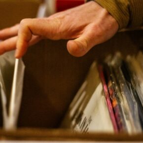 Main parcourant un bac de disques vinyles
