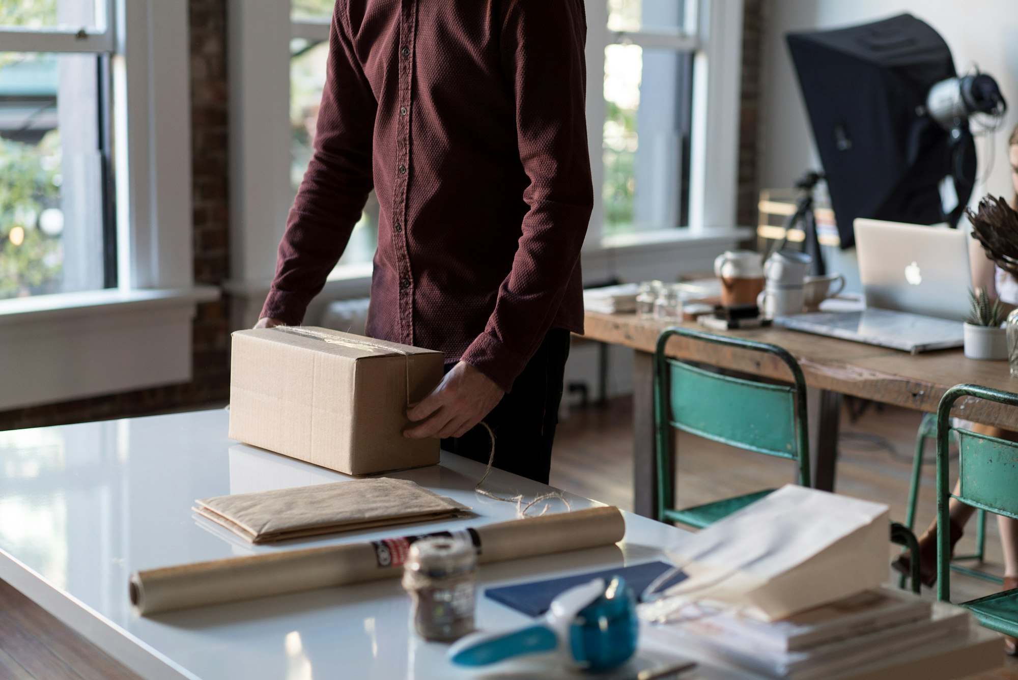 Personne tenant un carton d’expédition posé sur une table